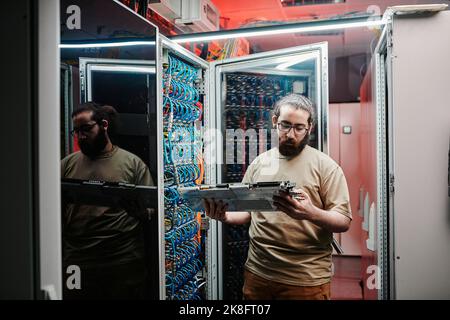 Computer technician checking machine part in data center Stock Photo