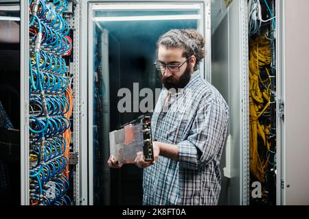 IT expert examining machine part in server room Stock Photo