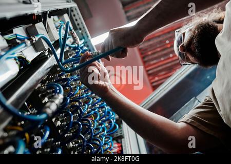 Technician connecting cables of server in data center Stock Photo