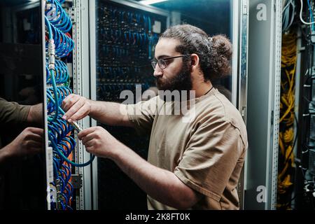 IT expert connecting computer cables in server room Stock Photo