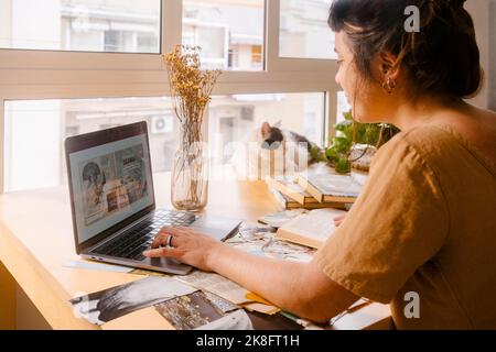 Freelance graphic designer working on laptop at desk in home Stock Photo