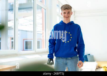 Happy teenage boy with amputated arm wearing European Union symbol hoodie Stock Photo