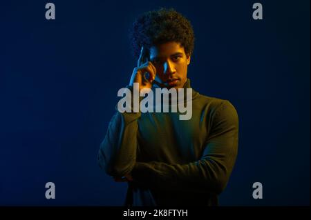 Young man holding finger to temple portrait Stock Photo