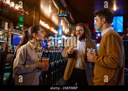 Cheerful friends talking drinking draft beer in pub Stock Photo
