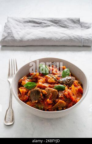 Caponata di melanzane.  Typical sicilian dish with eggplant, peppers, tomatoes and zucchini. Selective focus. Stock Photo