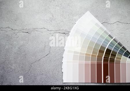 Paint samples colors swatch for interior design. Gray concrete cracked background, earth tone colors. Stock Photo