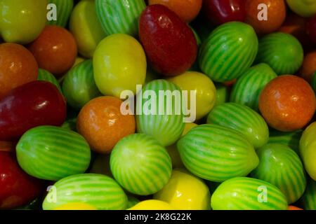A lot of chewy candies in the form of fruits: apple, orange, lemon, watermelon in a glossy glaze. Sweet bright background. Stock Photo