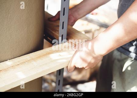 A carpenter measures the planks to assemble the parts, and build a wooden table for the customer. Stock Photo