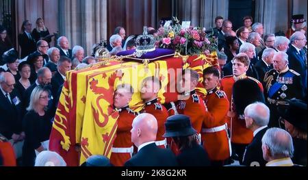 FUNERAL Queen Elizabeth II Funeral pall bearer party carry her Majesty’s coffin into the interior centre of Saint George’s Chapel with the Sovereign’s standard flag draped, the Crown Orb & Sceptre placed on top. King Charles II follows his mother’s coffin along with close members of The Royal Family. UHD Broadcast still.19th September 2022 Windsor Castle Berkshire UK Stock Photo
