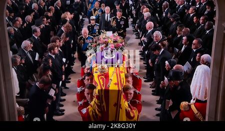 FUNERAL Queen Elizabeth II Funeral bearer party carry her Majesty’s coffin into the interior centre of Saint George’s Chapel with the Sovereign’s standard flag draped, the Crown Orb & Sceptre placed on top. King Charles II follows his mother’s coffin along with close members of The Royal Family. UHD Broadcast still.19th September 2022 Windsor Castle Berkshire UK Stock Photo