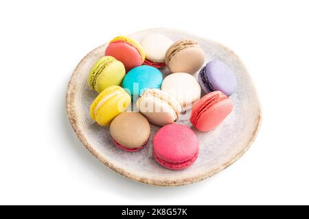 Multicolored macaroons on ceramic plate isolated on white background. side view, still life, close up. Breakfast, morning, concept. Stock Photo