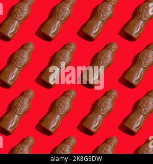 Pattern chocolate Santa Claus figure on a red background. Sweet Christmas candy. Close up sweet food for the holiday. Treat. Saint Nicholas chocolate figurine. Stock Photo