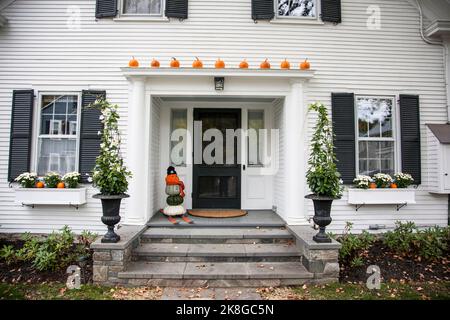Autumn decorations on a house front porch in Woodstock, Vermont, USA VT, US Halloween fall pumpkin man on skis New England, creative Stock Photo