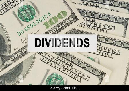 Business concept. On the dollars lies a paper plate with the inscription - Dividends Stock Photo