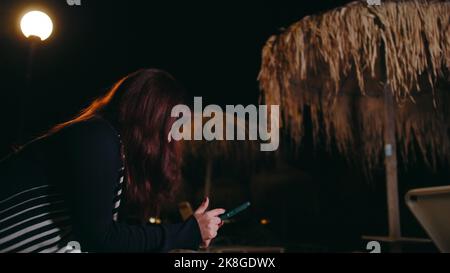Pretty Young Woman Flipping Through Phone Background Beach Night Stock Photo