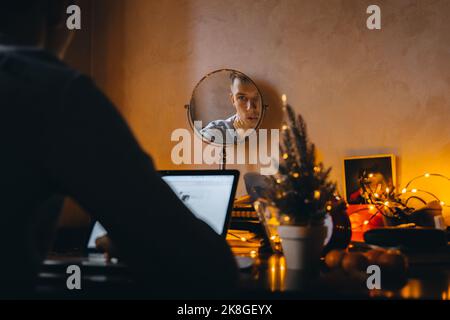 Concentrated freelance business man in typing on computer keyboard while working in home office interior decorated for Christmas holidays, male employ Stock Photo