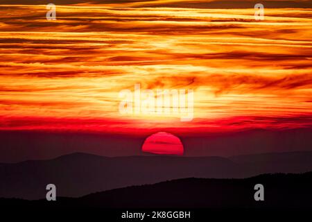 Big red setting sun with burning orange sky. Sunset in the mountains Stock Photo