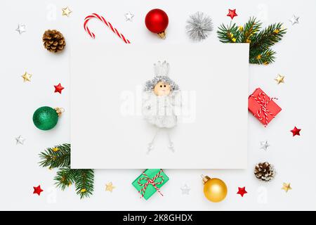 Christmas, New Year holiday layout. Small princess on blank white paper in frame of natural fir tree branches and pinecones, gifts, decorations on whi Stock Photo