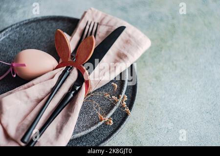 From above table set for Easter dinner with pink napkin and eggs on concrete background Stock Photo