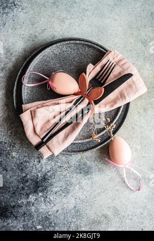 From above table set for Easter dinner with pink napkin and eggs on concrete background Stock Photo
