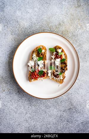 Sourdough bread toasts with cheese and roasted spiced tomato with oregano on the plate Stock Photo