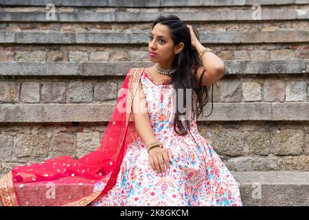 Thoughtful young Indian female in traditional sari outfit and looking away near ancient stone steps Stock Photo