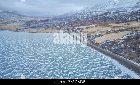 Aerial top view of uneven coast of calm dark sea covered with white snow on cold winter day in Iceland Stock Photo