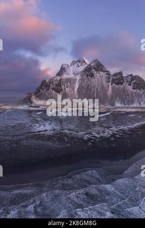 Aerial view of a snowy beach at sunset with ice formations along the ...