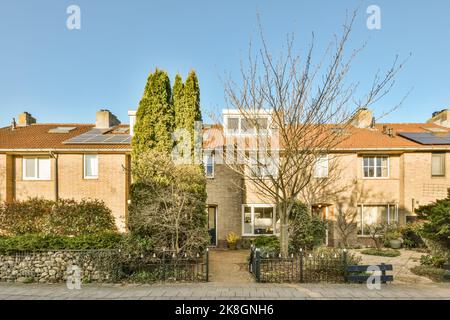 Exterior of modern residential house with brick walls tiled roof and decorative potted plants near entrance against blue sky in town Stock Photo