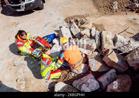 Emergency doctor and paramedic taking care of man on site of accident Stock Photo
