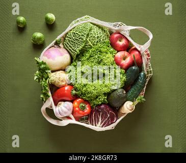 Ecological mesh bag with fresh fruits and vegetables on green background, top view. Zero-waste concept. Stock Photo