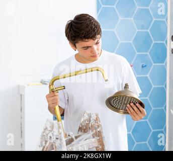 Focused guy assembling shower set before fixing to wall Stock Photo