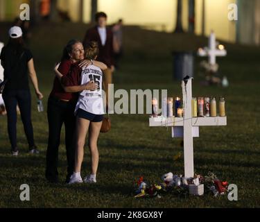 PARKLAND, FL - FEBRUARY 16: A young women places flowers at a memorial site that honors victims of the mass shooting at Marjory Stoneman Douglas High School, at Pine Trail Park on February 16, 2018 in Parkland, Florida. Police arrested 19-year-old former student Nikolas Cruz for killing 17 people at the high school.   People:  Atmosphere Stock Photo