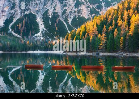 Red wooden boats on Braies lake at sunrise in autumn in Dolomites Stock Photo
