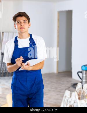 Focused contractor taking notes while planning renovation works in building Stock Photo