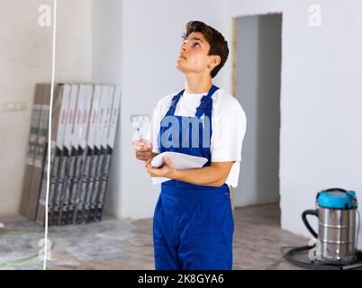 Young foreman making task list during works in building under construction Stock Photo