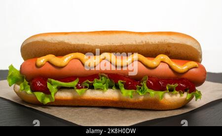 Freshly cooked hot dog lies on parchment paper before serving Stock Photo