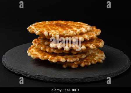 Fresh crispy Belgian waffles with a golden crust on a black stone plate on a black background Stock Photo
