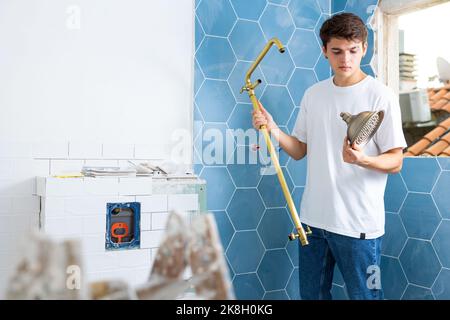 Focused guy assembling shower set before fixing to wall Stock Photo