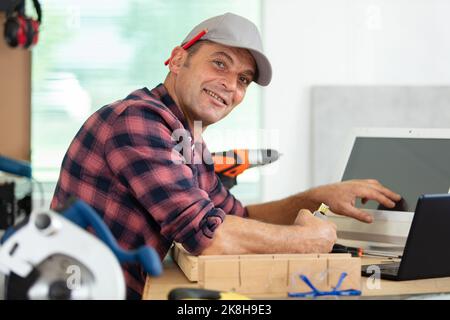 portrait of modern senior carpenter using laptop Stock Photo