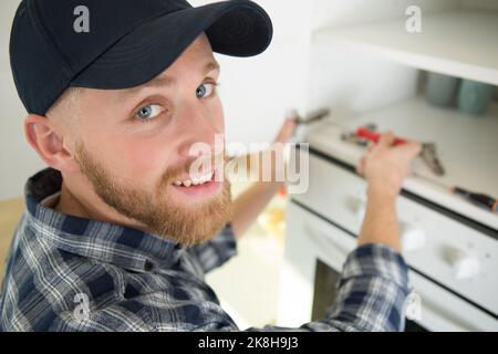 closeup of young man repairing oven Stock Photo