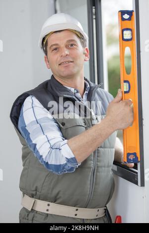 workman checks window with a spirit level Stock Photo