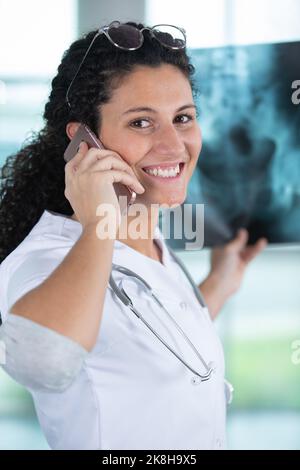 doctor woman hold x ray scan while talking on phone Stock Photo