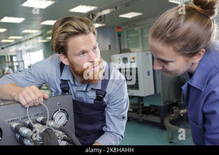 engineer helping female apprentice in factory Stock Photo