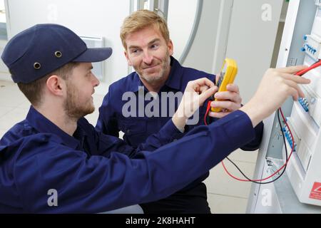 electrician measuring voltage in distribution board Stock Photo