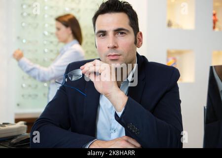 portrait of suited man holding eyeglasses in the opticians Stock Photo