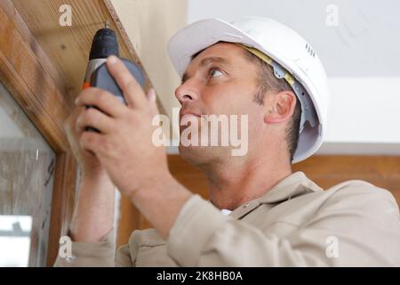 builder using drill on wooden lintel Stock Photo