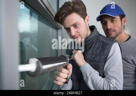 technician and apprentice using a silicon gun Stock Photo