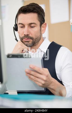 concentrated bearded man in suit holding clipboard in office Stock Photo