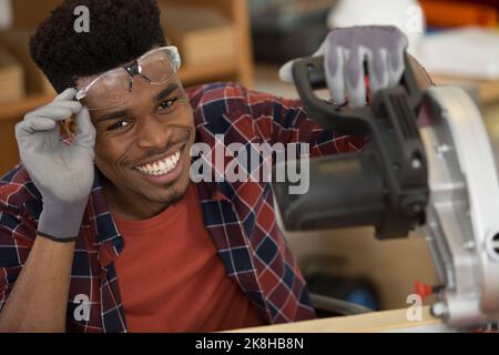 happy male carpenter with circular saw in woodworking Stock Photo